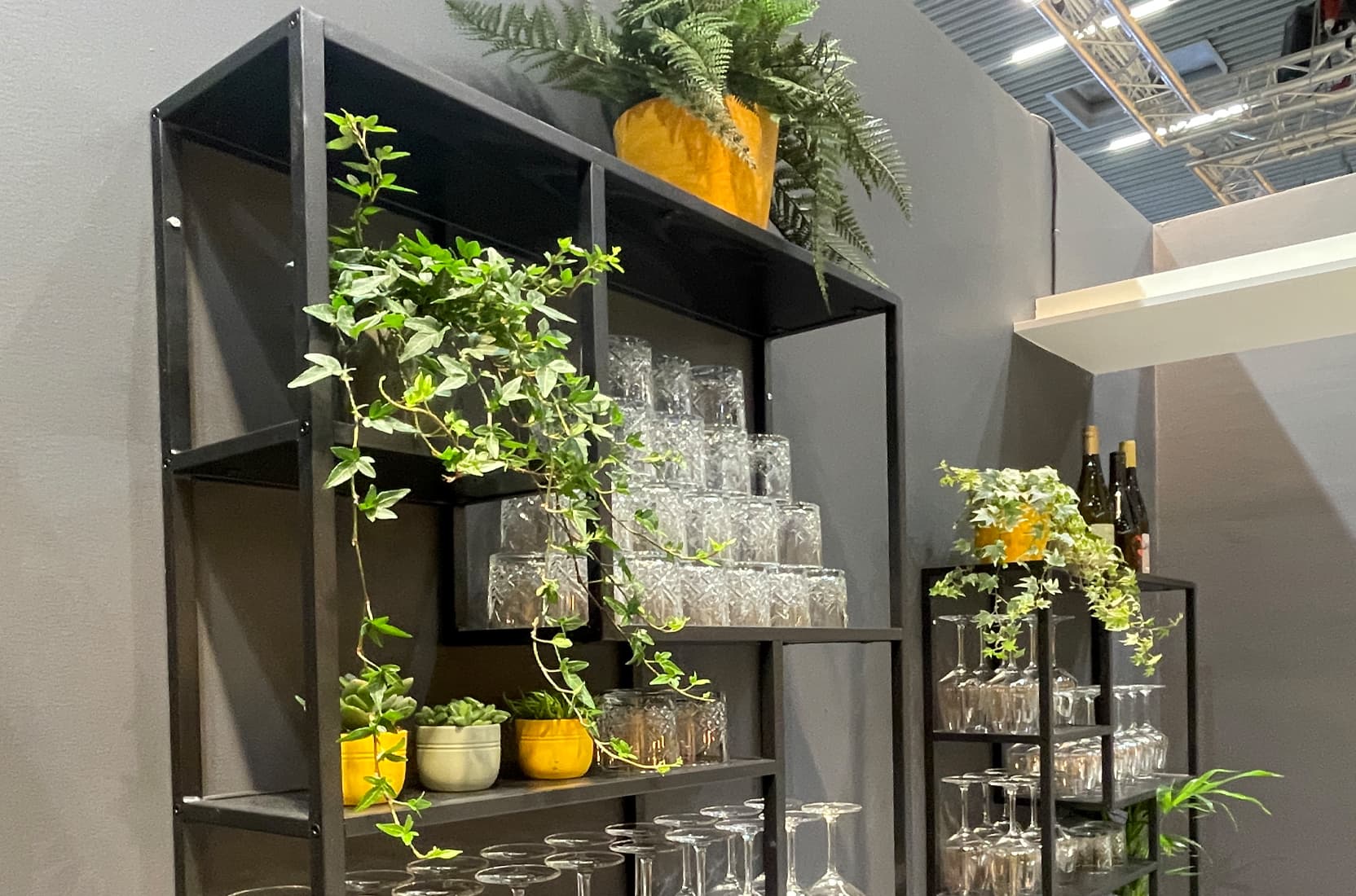 Regale mit Gläsern und Pflanzen in der Bar auf dem Sika-Messestand